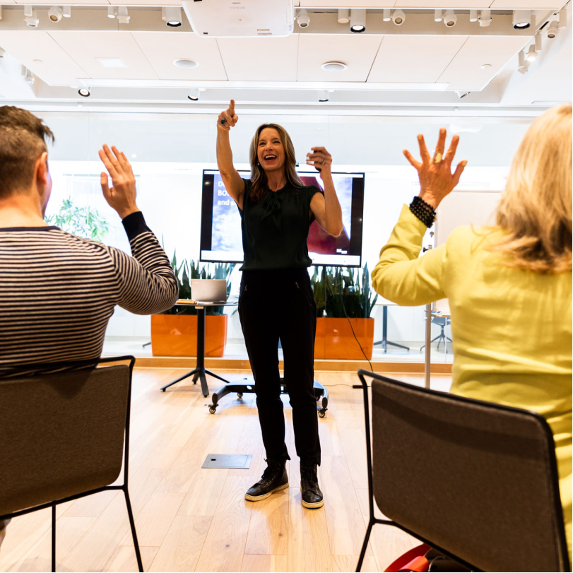 Woman leading a professional development workshop while people raise their hands
