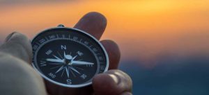 Man holding a compass at sunset thinking about the Bold Vision exercise
