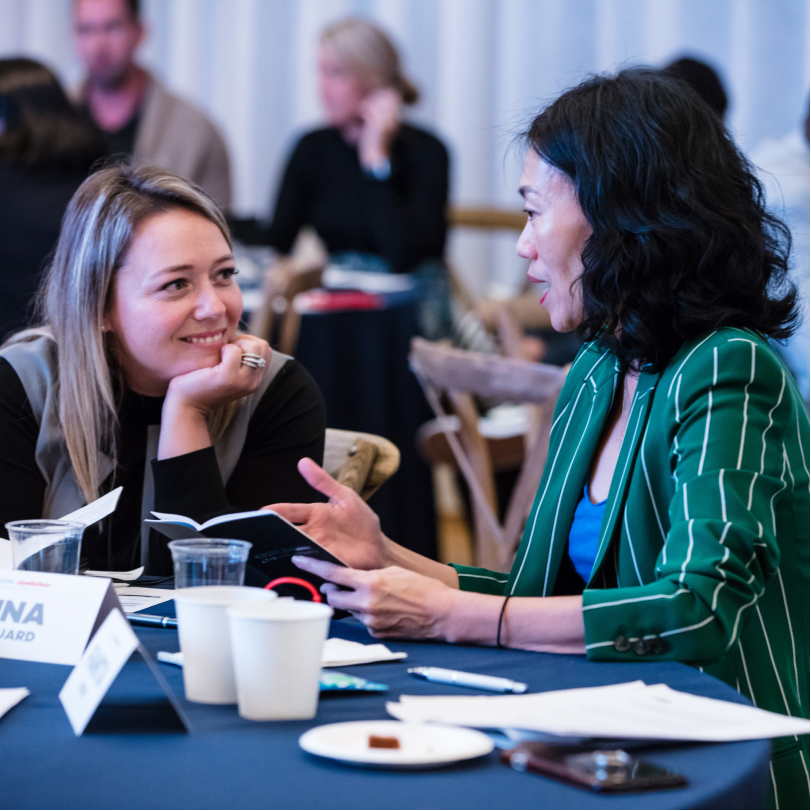 Two woman happily discussing a sales team development strategy at a table