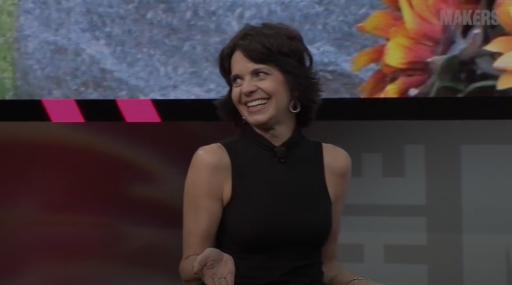 Woman smiling in front of a TV discussing motivational speakers