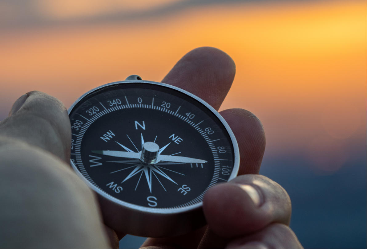 Man holding a compass at sunset contemplating corporate training programs
